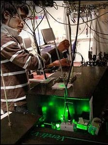 Koji Usami, one of the researchers involved in the paper, maneuvering the experiment at the  Quantop laboratories at the Niels Bohr Institute. The laser light that hits the semiconducting nanomembrane is controlled with a forest of mirrors. (c) Niels Bohr Institute 