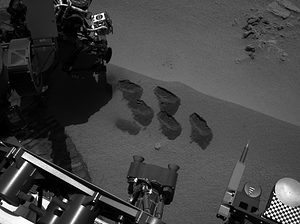 ASA's Mars rover Curiosity used a mechanism on its robotic arm to dig up five scoopfuls of material from a patch of dusty sand called "Rocknest," producing the five bite-mark pits visible in this image from the rover's left Navigation Camera (Navcam). Each of the pits is about 2 inches (5 centimeters) wide. Image credit: NASA/JPL-Caltech