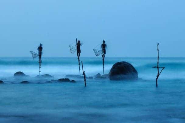 Photo and caption by ulrich lambert      Stilt fishing is a typical fishing technique only seen in Sri Lanka. The fishermen sit on a cross bar called a petta tied to a vertical pole planted into the coral reef. This long exposure shot shows how unstable their position is. Photo Location     Midigama, Sri Lanka  
