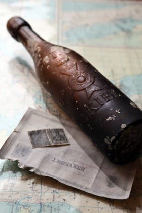 A postcard dated 17 May 1913 and the old beer bottle sit on top of a map in Kiel, Germany. Photograph: Uwe Paesler/EPA