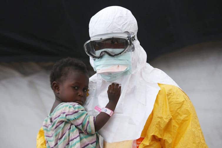 A Doctors Without Borders health worker in protective clothing holds a child suspected of having Ebola in Paynesville, Liberia. Image: Getty