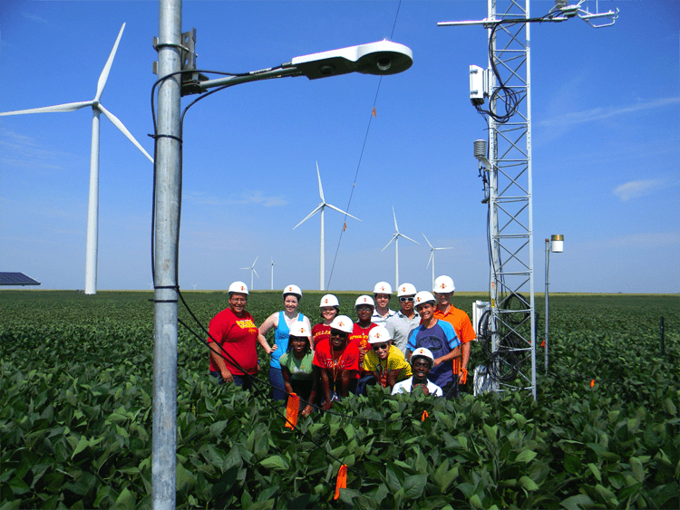 Iowa State students from the College of Engineering's Summer Program for Enhancing Engineering Development (SPEED) program pose near wind turbines and meteorological towers on an Iowa windfarm. Photo: IOWA EPSCOR