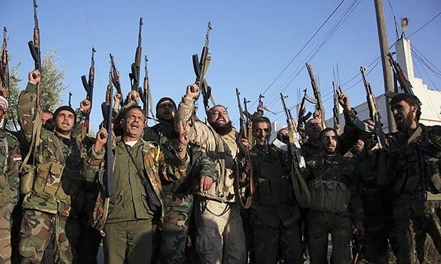 Soldiers loyal to Assad cheer while raising their weapons in the Aleppo countryside. Photograph: George Ourfalian/Reuters