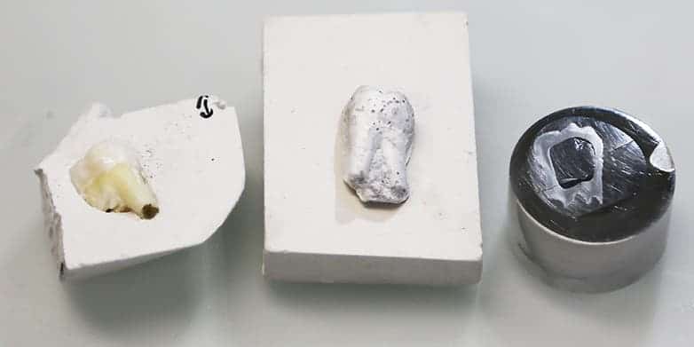 The left structure is showing the natural tooth in its gypsum mold, the middle structure is the artificial tooth (sintered but not yet polymer infiltrated). The model on the right has been sintered and polymer infiltrated. It is embedded in a 