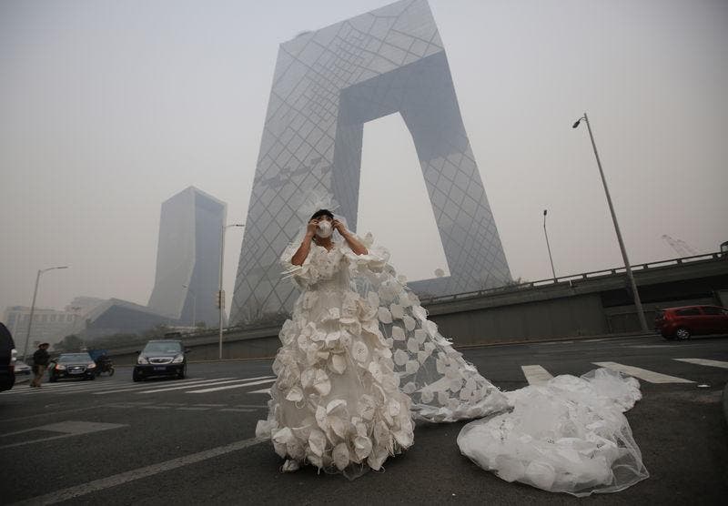 Kong Ning wears a wedding dress decorated with 999 face masks for her performance art work 'Marry the blue sky' as she poses for a photograph in front of the China Central Television (CCTV) Headquarters on a hazy day in Beijing November 19, 2014. Wearing a 10 meter-long wedding dress decorated with face masks is a part of Kong Ning's performance art work which signifies her frustration with air pollution.   REUTERS/Kim Kyung-Hoon