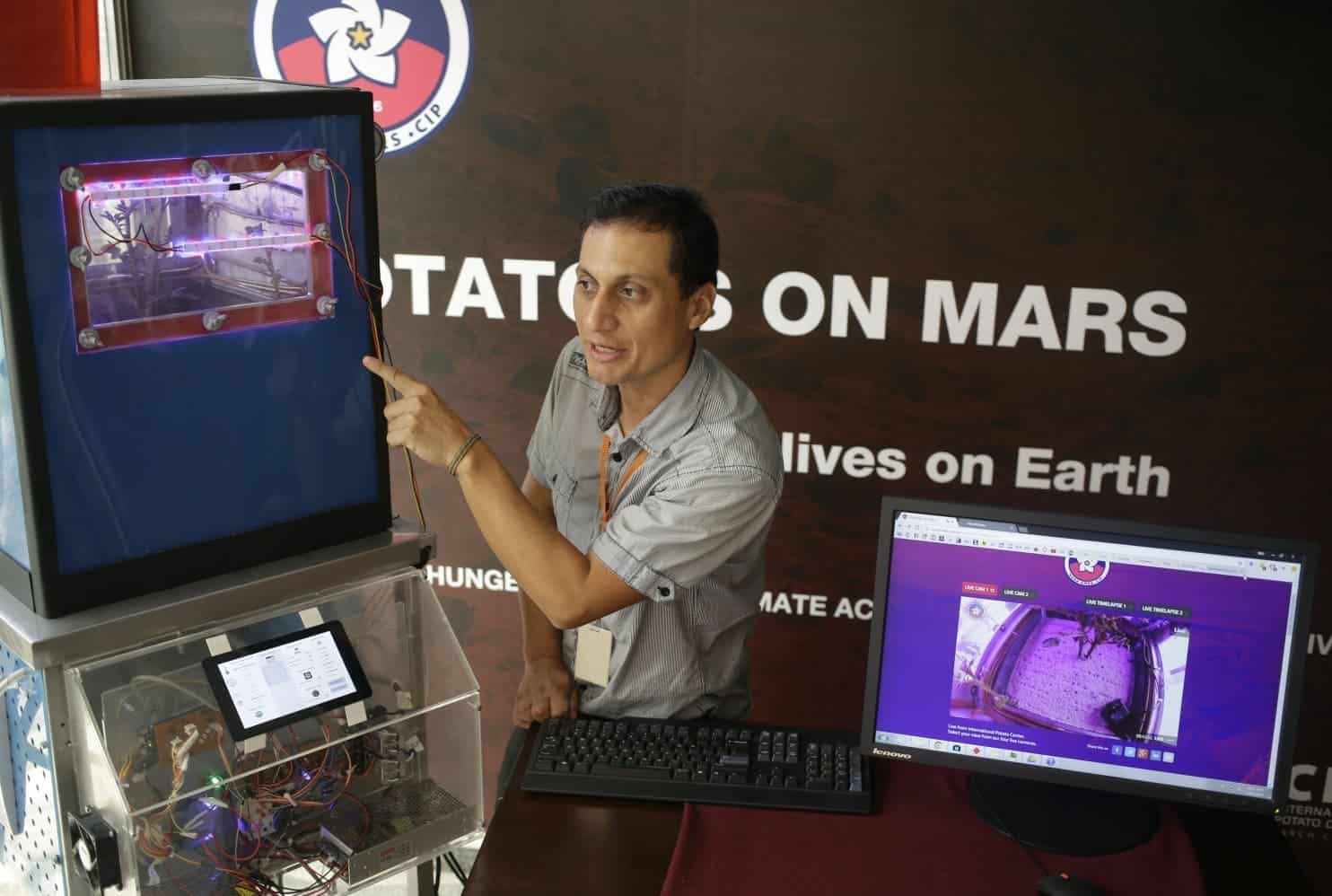 Peruvian scientist David Ramirez points to a potato plant in a simulator akin to a Mars’ conditions, in Lima Peru.