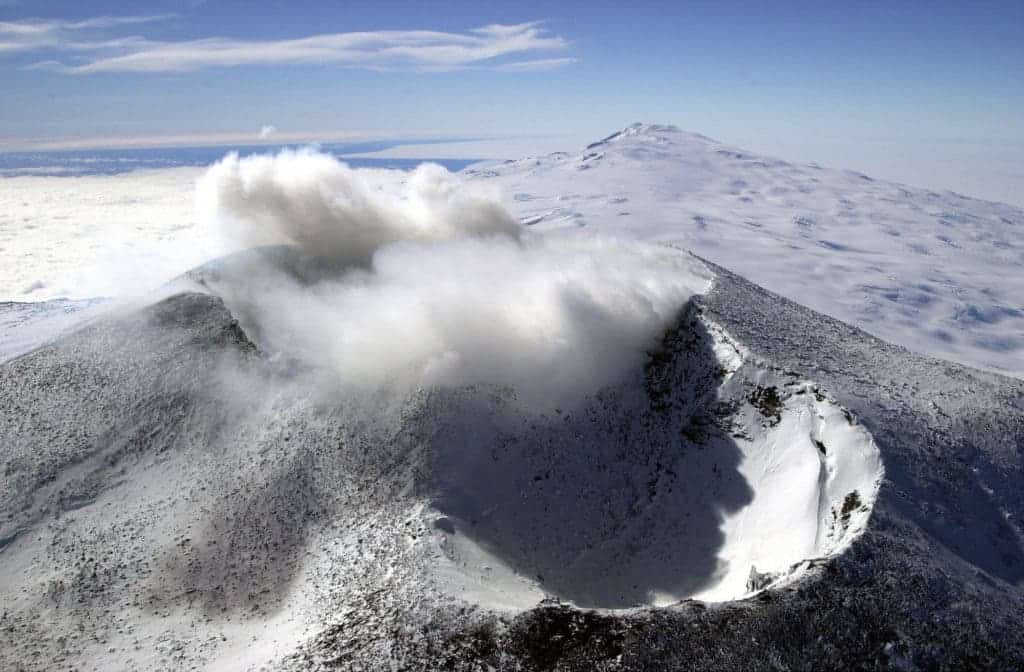 Aerial photo of Mount Erebus gushing smoke and ash from Ross Island, Antarctica. Credit: Wikimedia Commons.