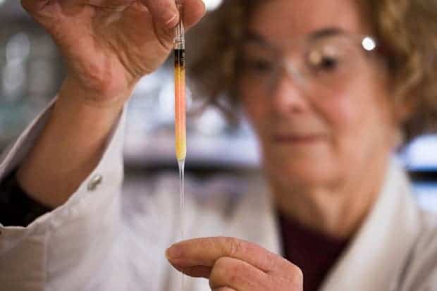 Biogeochemistry lab manager Janet Hope holds a vial of coloured porphyrins (pink coloured liquid), which researchers believe to be some of the oldest pigments in the world. Photograph: Lannon Harley/Australian National University.