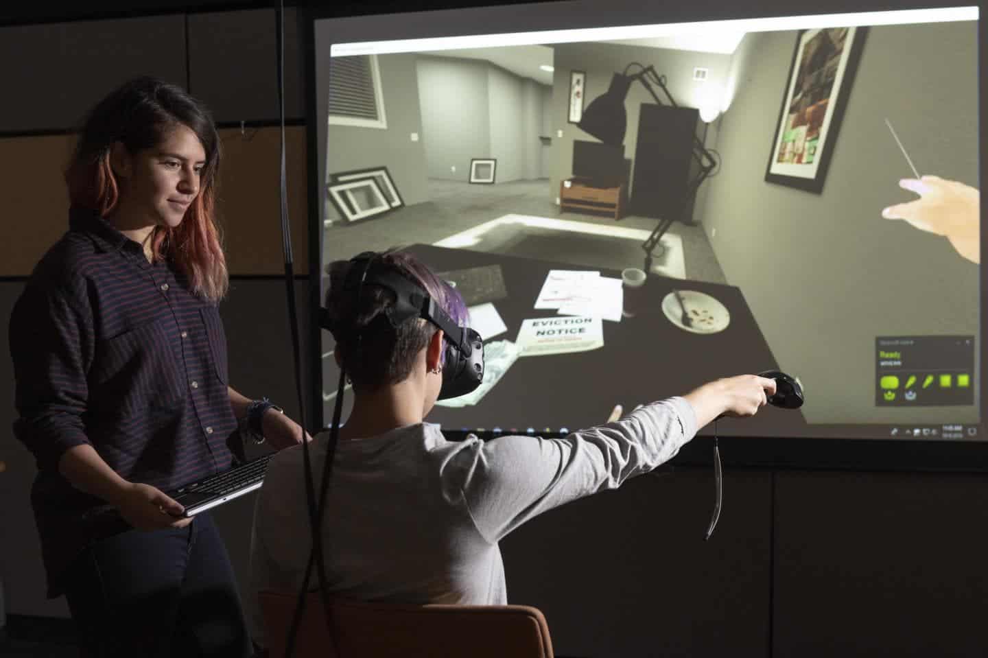 Stanford researcher supervises a student while he navigates through a VR experience that simulates what it feels like becoming homeless. The scene shown here is that of an eviction notice. Credit:  L.A. Cicero.