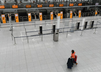 A woman wheels her luggage through an empty check in hall of a terminal of the Franz-Josef-Strauss airport in Munich, southern Germany on March 17, 2020 where many flights are currently cancelled by the airlines because of the new coronavirus COVID-19. (Photo by Christof STACHE / AFP) (Photo by CHRISTOF STACHE/AFP via Getty Images)