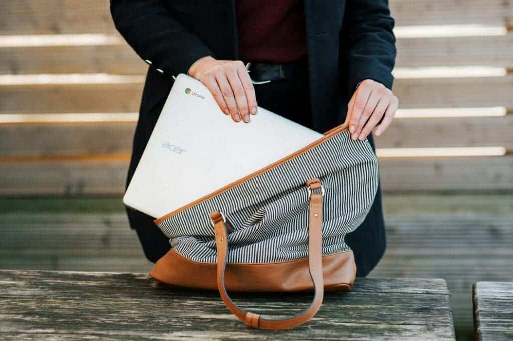 a man packing a chromebook in his bag