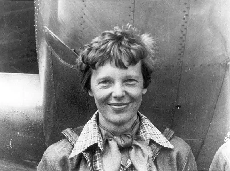 Earhart beneath the nose of her Lockheed Model 10-E Electra, March 1937, Oakland, California, before departing on her final round-the-world attempt prior to her disappearance. Credit: Wikimedia Commons.
