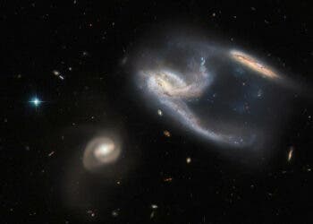 The subject of this image is a group of three galaxies, collectively known as NGC 7764A. They were imaged by the NASA/ESA Hubble Space Telescope, using both its Advanced Camera for Surveys (ACS) and Wide Field Camera 3 (WFC3). The two galaxies in the upper right of the image appear to be interacting with one another — indeed, the long trails of stars and gas extending from them both give the impression that they have both just been struck at great speed, thrown into disarray by the bowling-ball-shaped galaxy to the lower left of the image. In reality, however, interactions between galaxies happen over very long time periods, and galaxies rarely collide head-on with one another. It is also unclear whether the galaxy to the lower left is actually interacting with the other two, although they are so relatively close in space that it seems possible that they are. By happy coincidence, the collective interaction between these galaxies have caused the two on the upper right to form a shape, which from our Solar System's perspective, ressembles the starship known as the USS Enterprise from Star Trek! NGC 7764A, which lies about 425 million light years from Earth in the constellation Phoenix, is a fascinating example of just how awkward astronomical nomenclature can be. The three galaxies are individually referred to as NGC 7764A1, NGC 7764A2 and NGC 7764A3, and just to be really difficult, an entirely separate galaxy, named NGC 7764, sits in the skies about a Moon’s distance (as seen from Earth) away. This rather haphazard naming makes more sense when we consider that many of the catalogues for keeping track of celestial bodies were compiled well over 100 years ago, long before modern technology made standardising scientific terminology much easier. As it is, many astronomical objects have several different names, or might have names that are so similar to other objects’ names that they cause confusion.