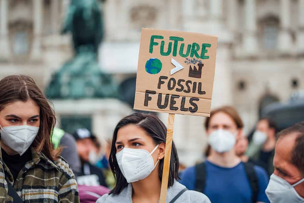 A woman holds a banner against fossil fuels