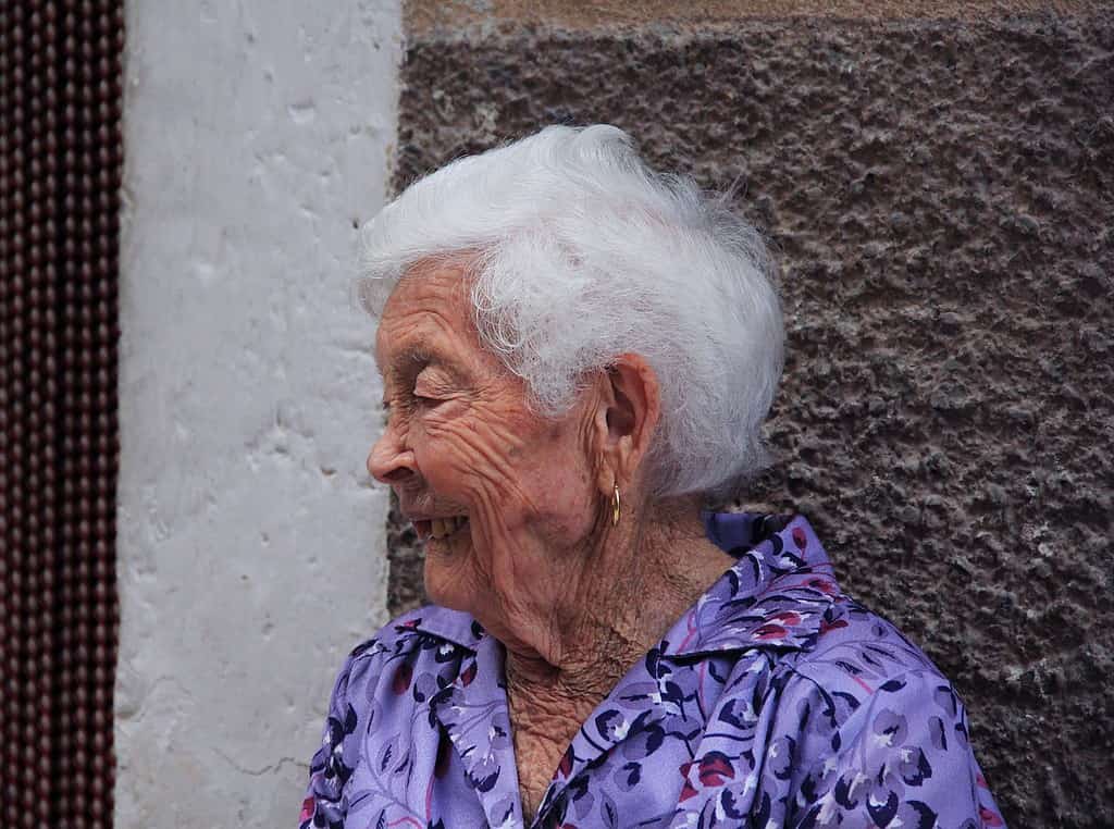 An elderly woman is seen smiling 