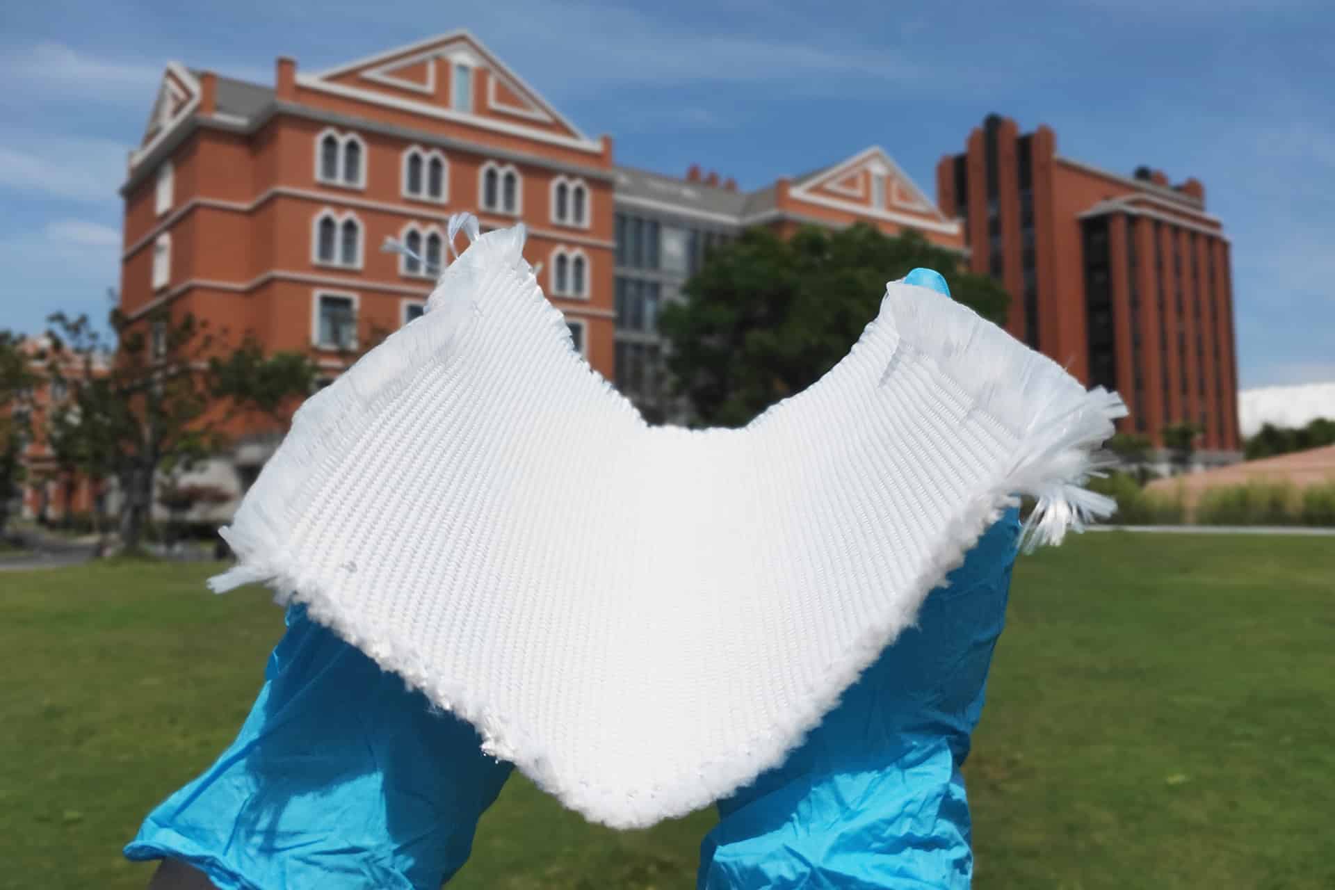 A researcher holding the thermal cloak fabric in their hands.