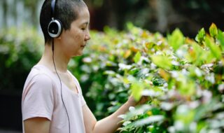 A woman touching plants while listening to music on headphones.